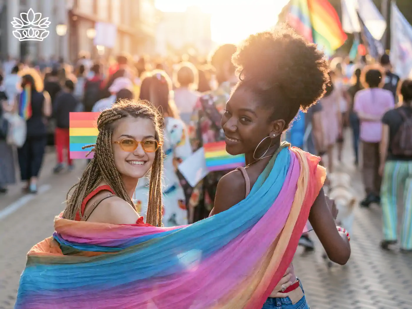 Two women with rainbow shawls enjoying a Pride parade, smiling and celebrating. Fabulous Flowers and Gifts - Pride Collection.