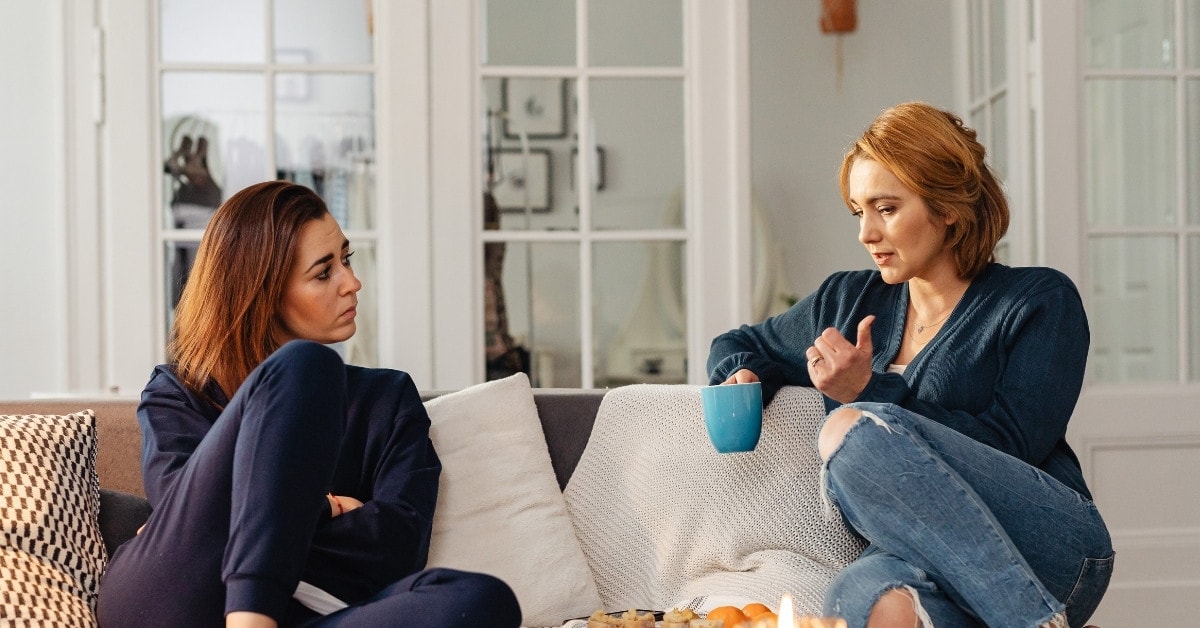 Two women sitting and talking about what is the tax advice for OnlyFans?