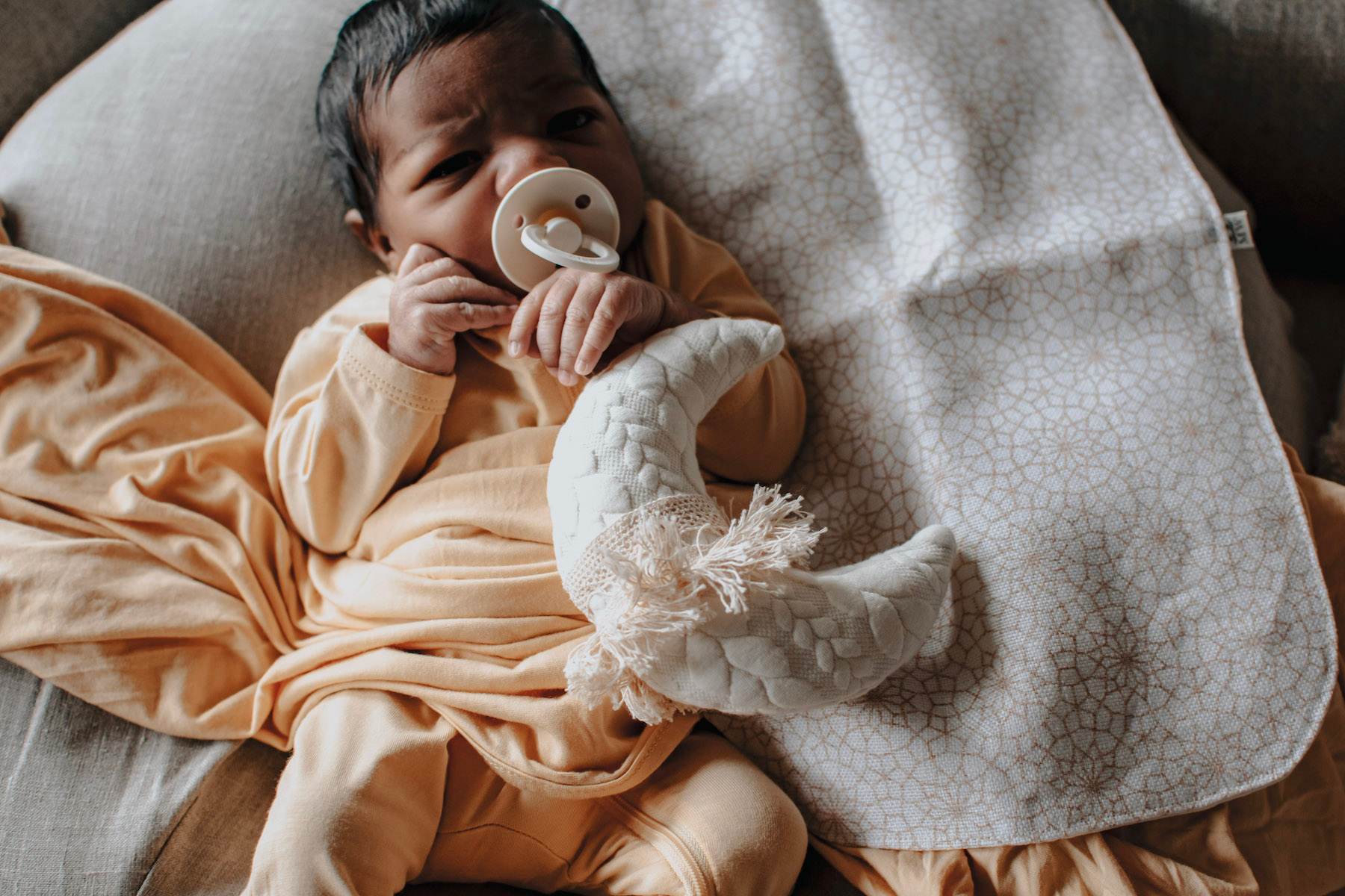 Newborn baby resting on a nursing pillow with a burp cloth