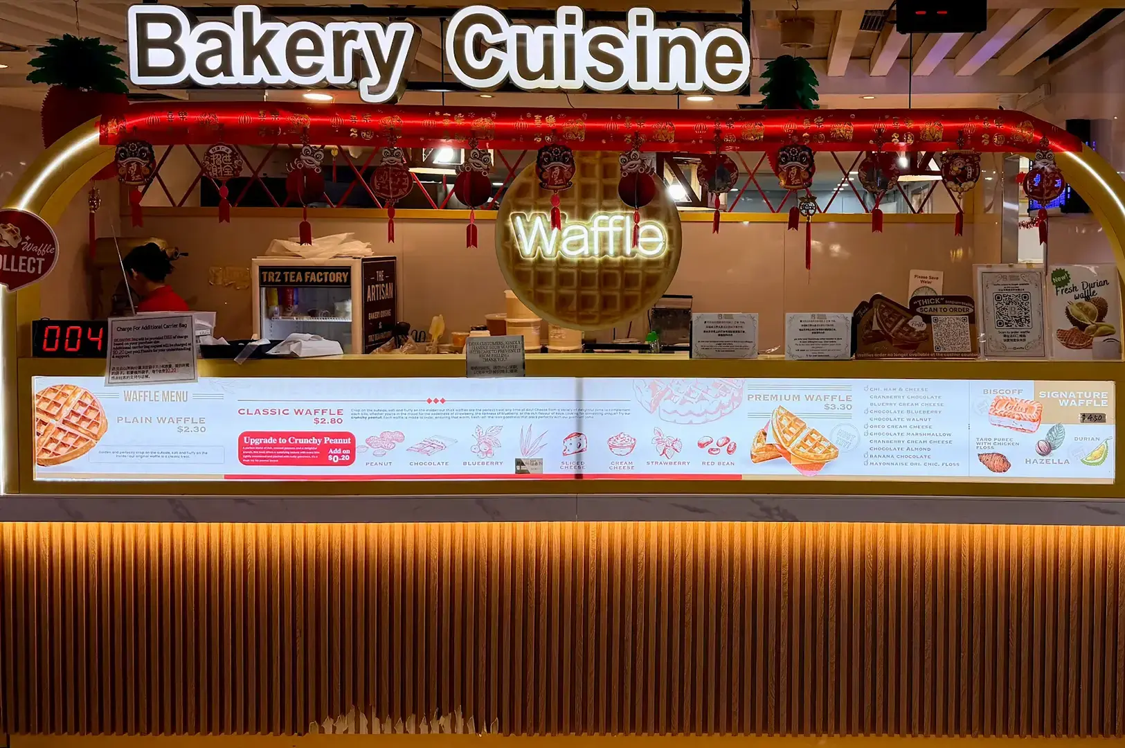 Bakery Cuisine storefront with red neon signage, waffle neon sign, counter with menu graphics, and warm lighting.
