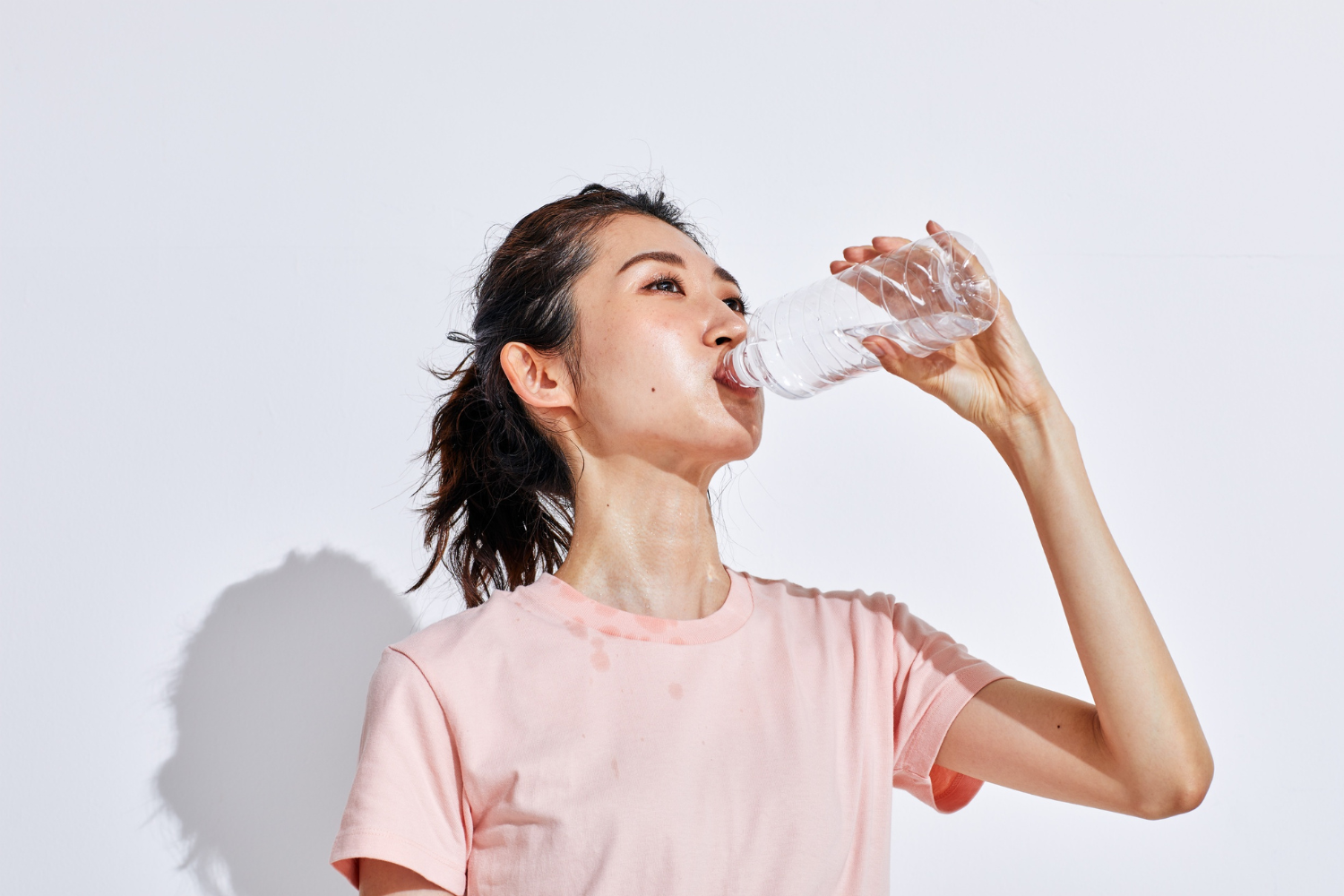 Woman drinking water from a clear water bottle.