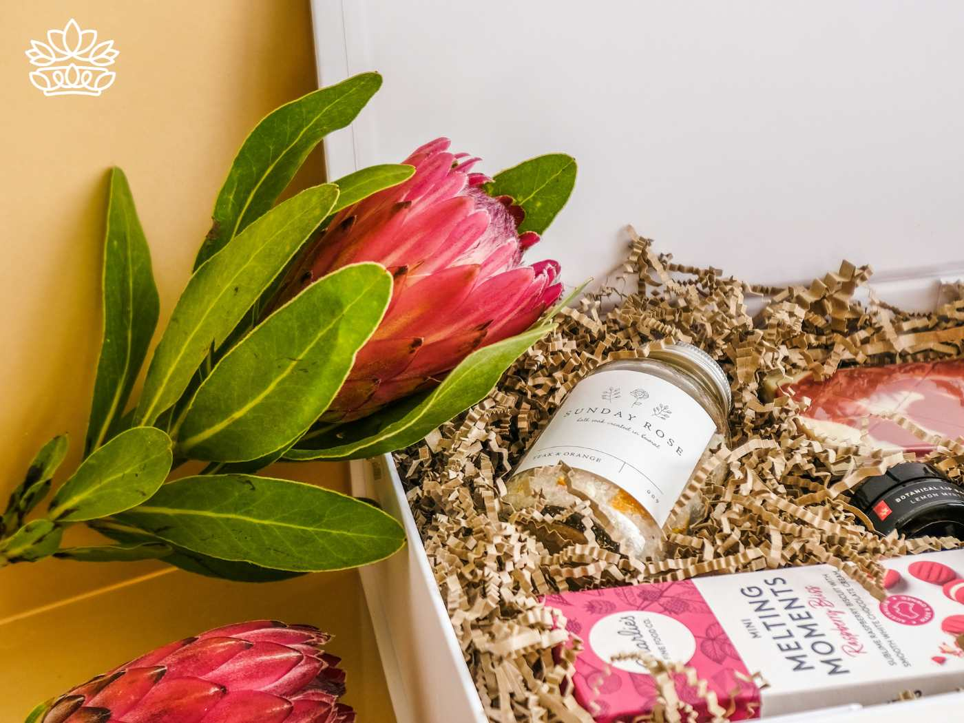 A beautifully arranged gift hamper containing protea flowers, bath salts, and chocolates, representing the Gift Boxes for Her Collection - Perfect for friends - Fabulous Flowers and Gifts
