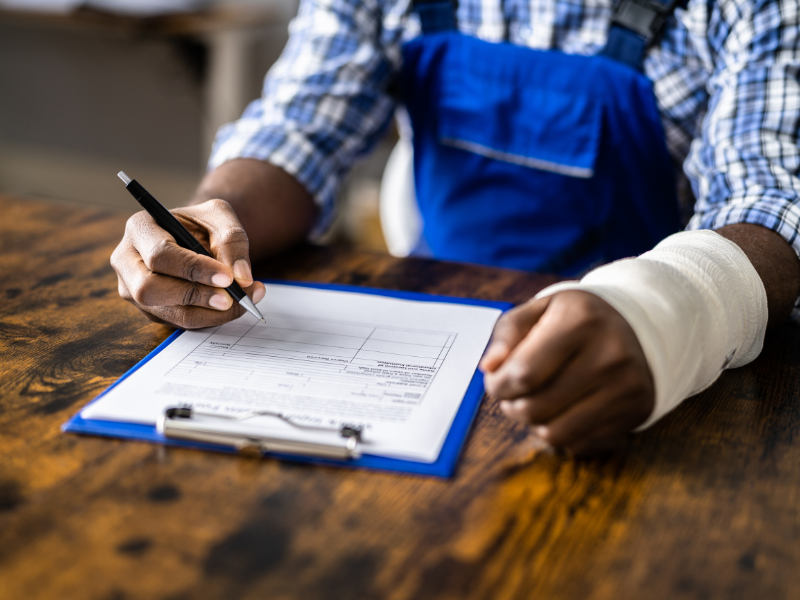 An image of a person filling out claim forms after an auto accident settlement.