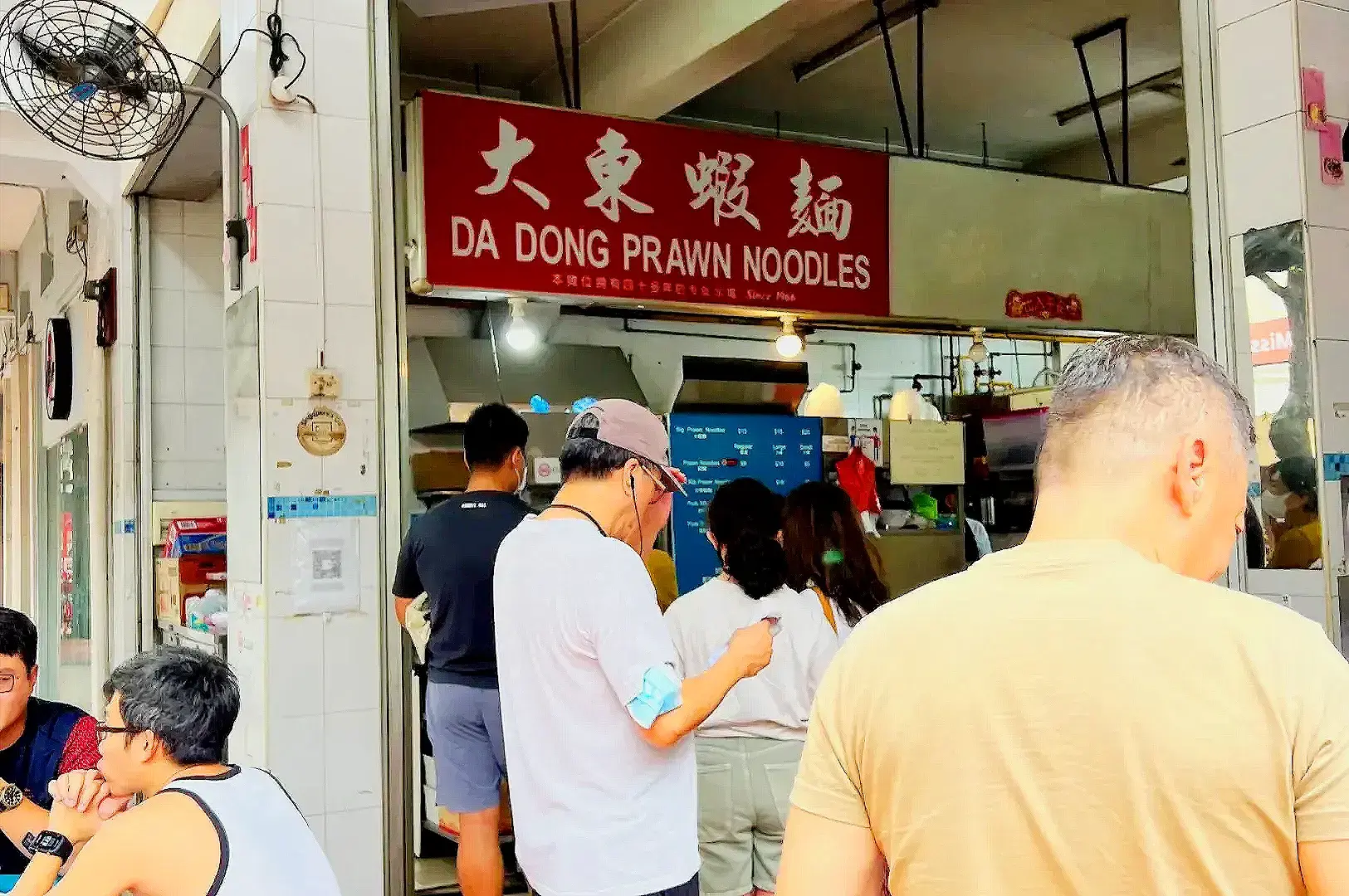 Da Dong Prawn Noodles Singapore storefront with customers ordering traditional prawn mee