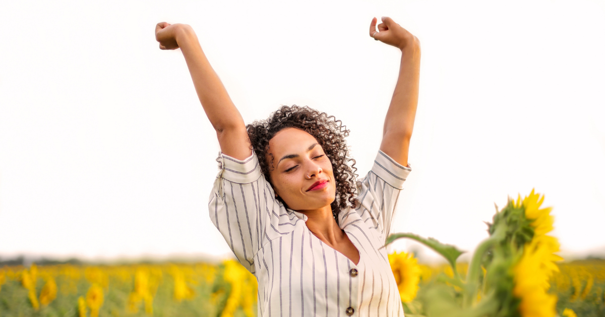 A happy woman throwing her arms up with increased energy and alertness from cold plunging.