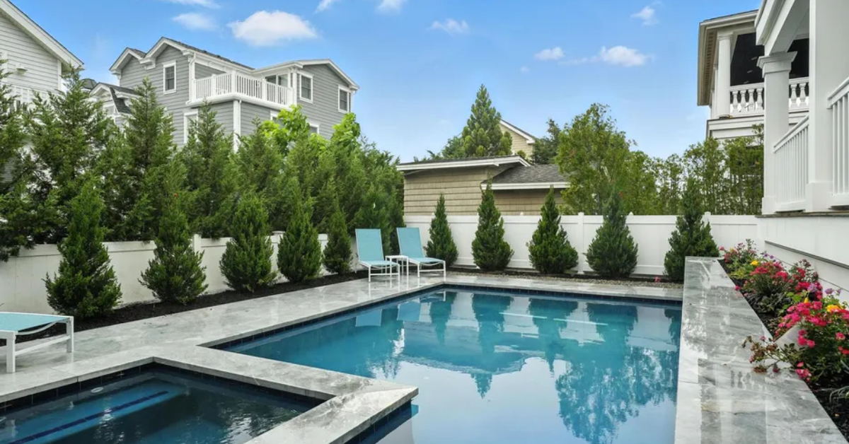 Image of a private backyard pool at a luxury Avalon, NJ vacation rental surrounded by coastal homes and landscaped fencing