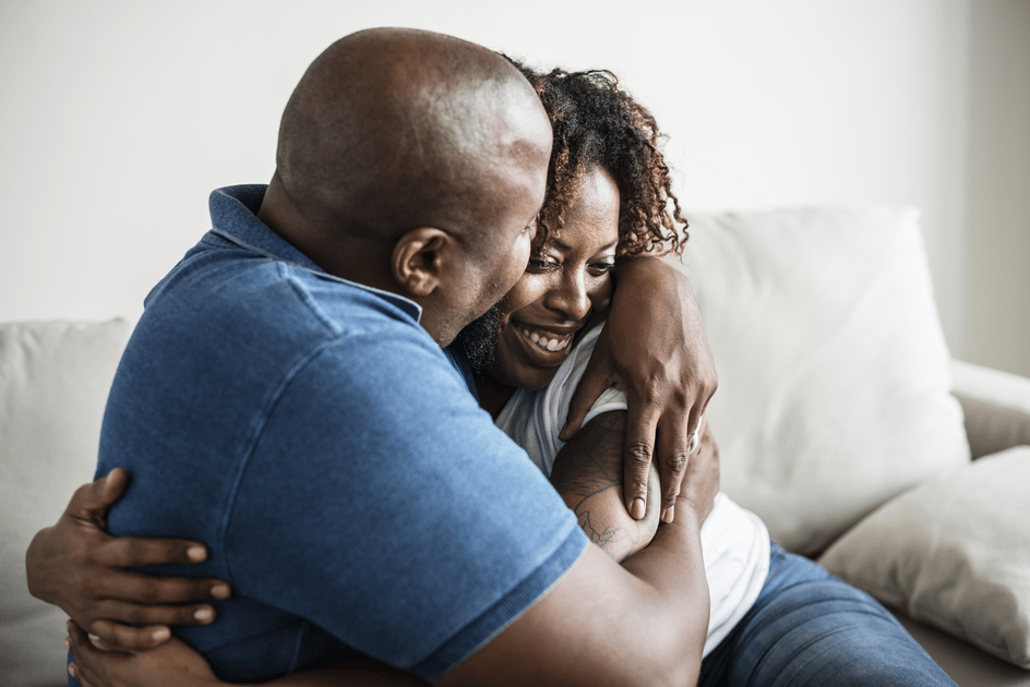 Couple hugging on sofa, celebrating progress in overcoming ADHD-related challenges in marriage, strengthening relationship through understanding and support.
