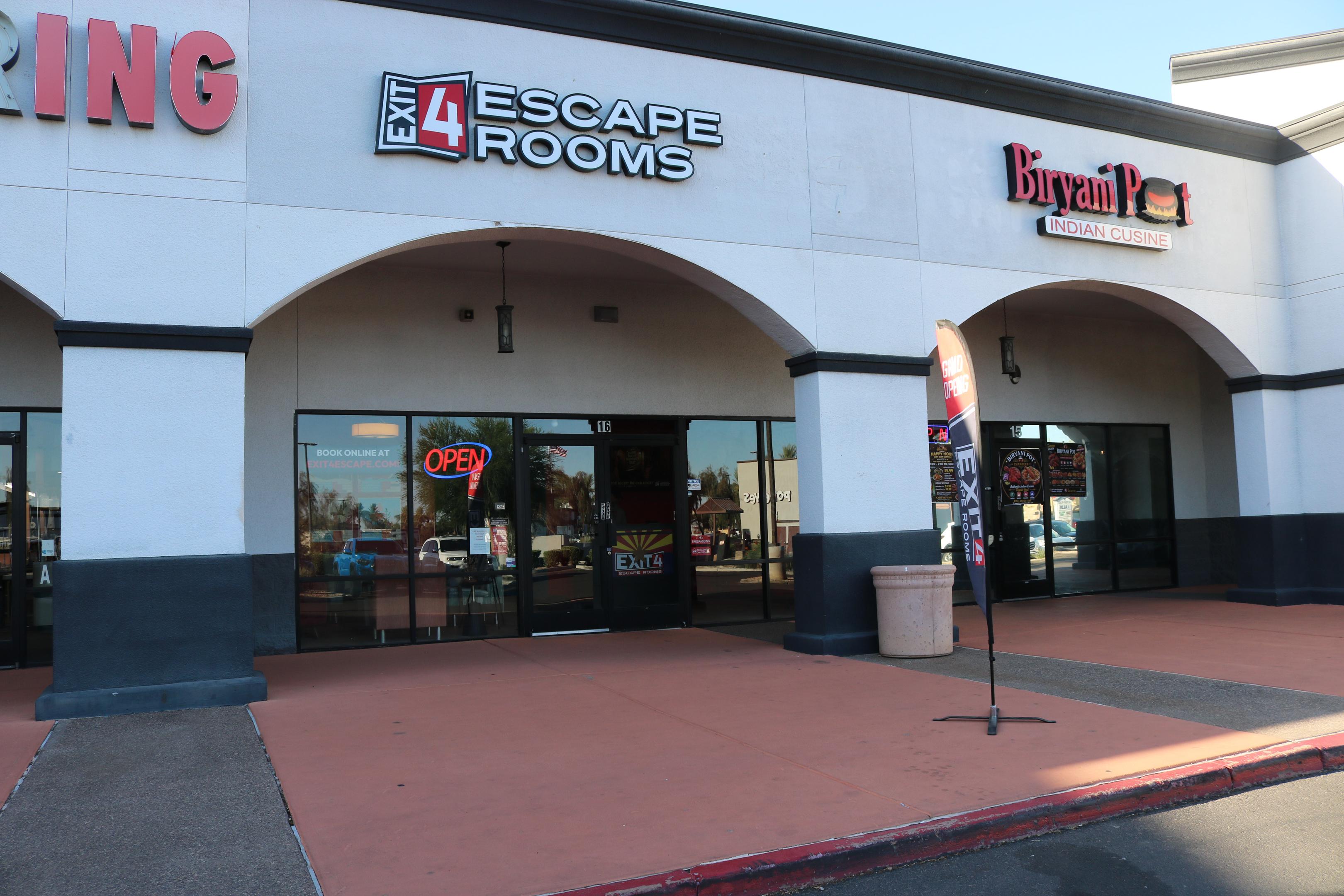 The image depicts a welcoming storefront entrance of an escape room venue, adorned with colorful signage that enhances the inviting atmosphere as dusk settles. This location is perfect for team building events, where groups can enjoy a fun experience solving puzzles and uncovering clues together.