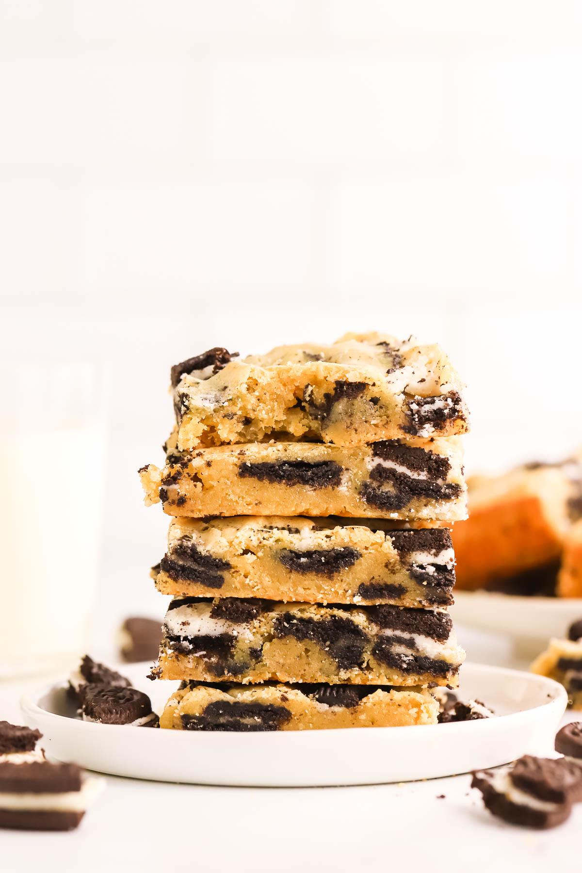 five baked Oreo blondies stacked on top of a white plate