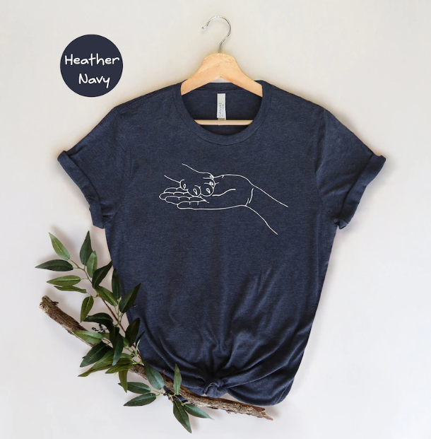 Navy Blue -shirt on hanger with an image of a human hand holding a dog paw.