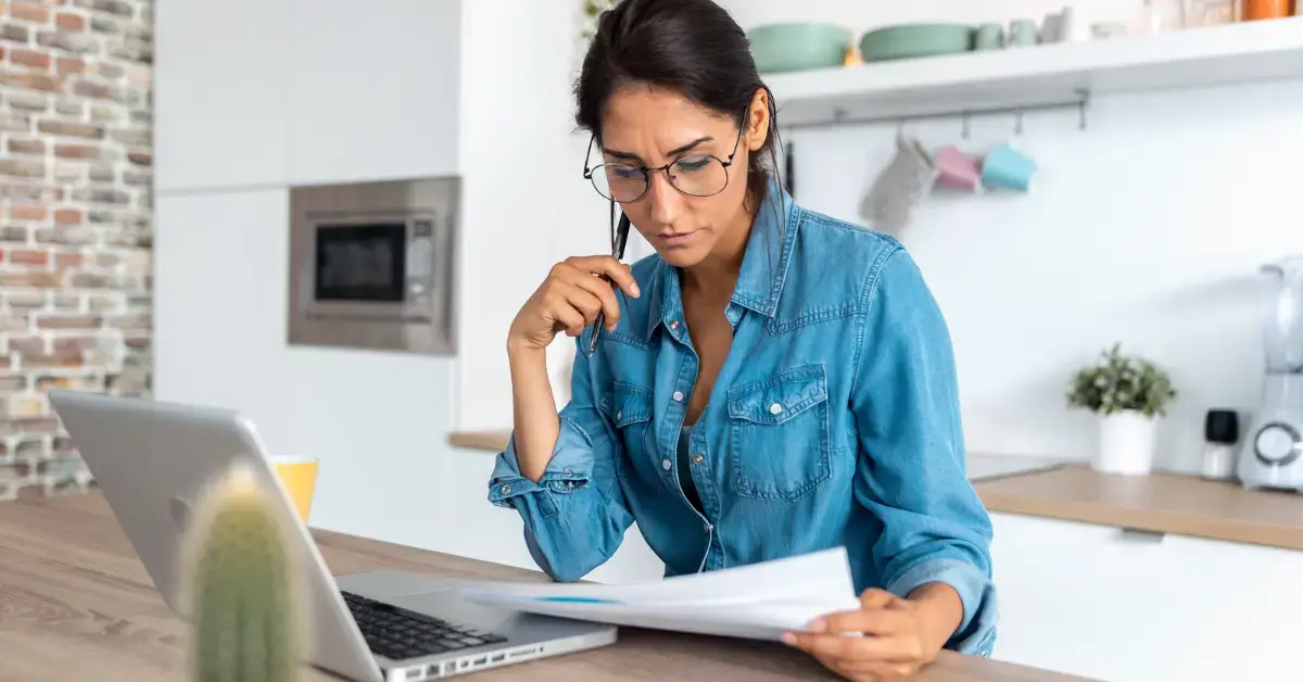 Woman reviewing IRS debt and mortgage paperwork while researching if you owe IRS can you buy house.