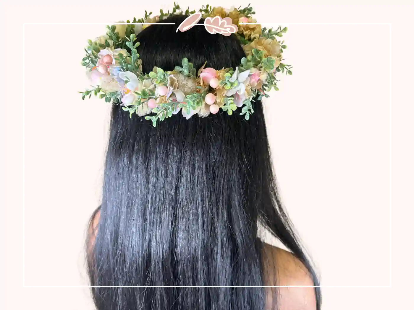 A woman with long black hair wearing a delicate floral crown with pink and white flowers. Blushing Beauty Floral Crown by Fabulous Flowers and Gifts.