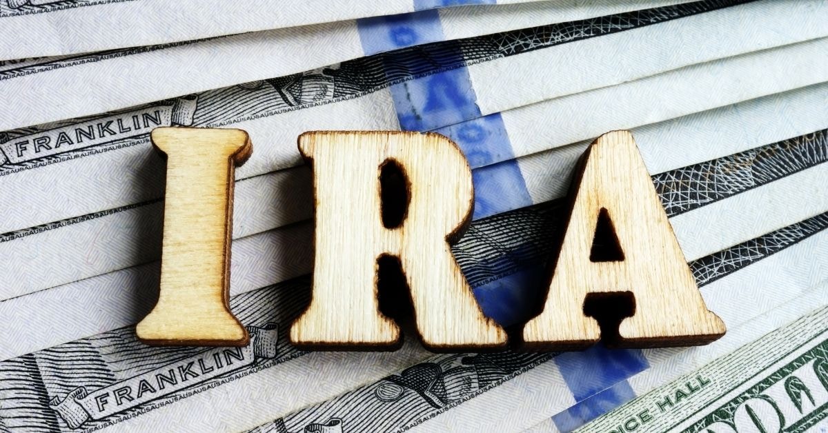 OnlyFans IRA options displayed with wooden letters 'IRA' on U.S. currency notes, highlighting retirement.