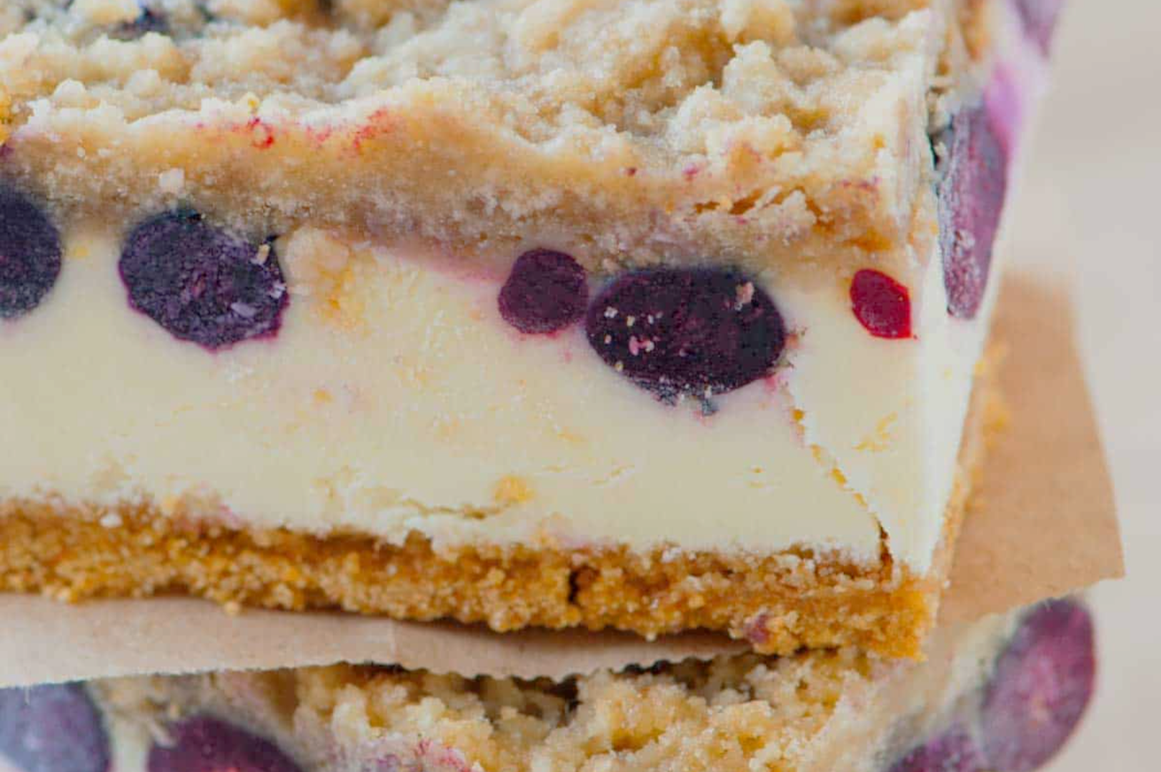 Close-up of a blueberry cheesecake bar with a crumbly streusel topping. It has a golden crust, creamy layer, and vibrant blueberries. Indulgent and inviting.