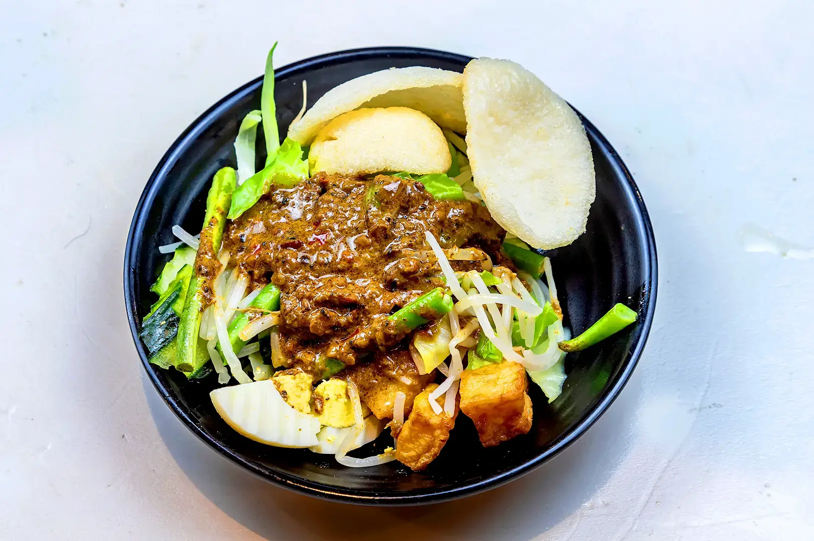 Indonesian gado-gado with vegetables, tofu, bean sprouts, boiled egg, peanut sauce and crackers