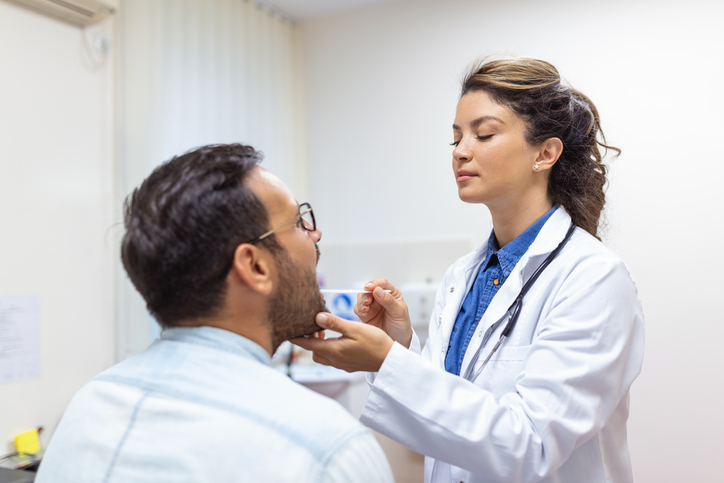 An image of a doctor examining a patient's throat. 