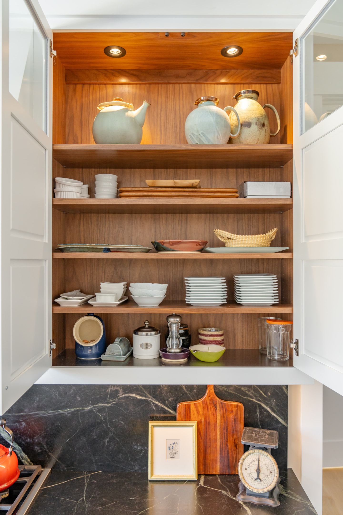 Photo of open cabinet doors revealing the interior of cabinets holding items, including pantry items like sugar and salt.