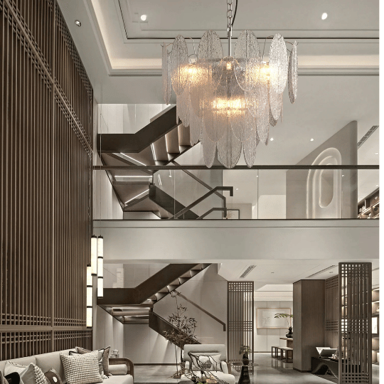 Luxurious chandelier with layered glass panels and warm golden light creating a sophisticated glow in a double-height modern foyer.