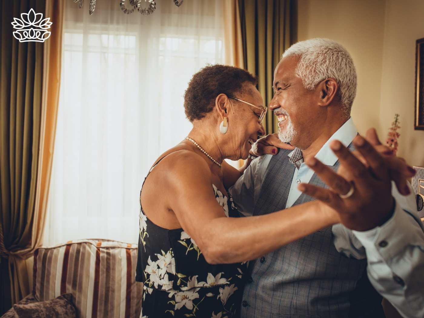Joyful elderly couple dancing in their living room, sharing a laugh and enjoying a moment of love, showcasing lifelong companionship and happiness. Fabulous Flowers and Gifts. Delivered with Heart.