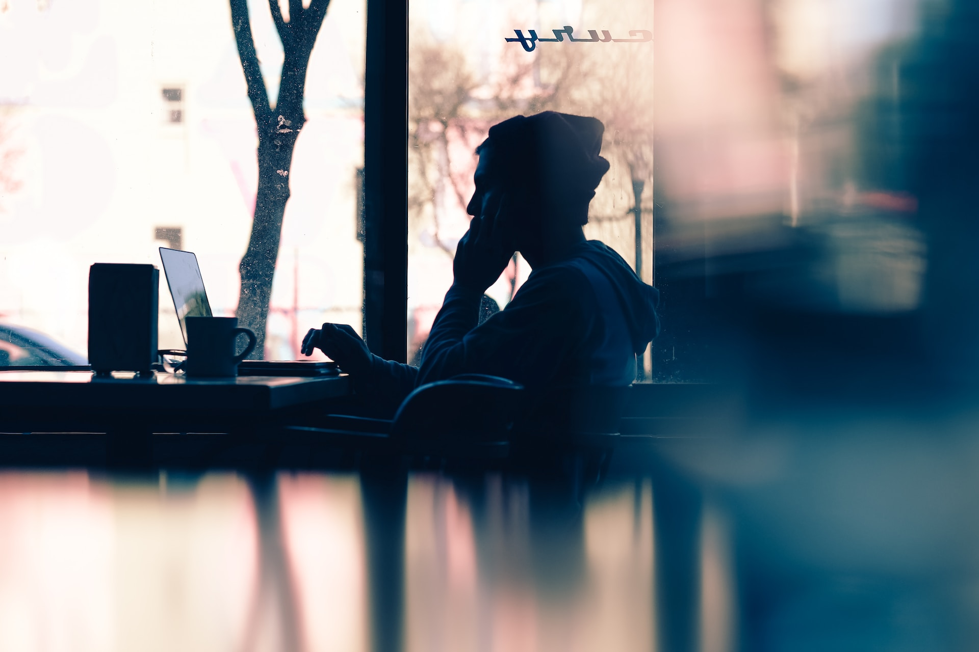 silhoutte of a person sitting in front of a laptop