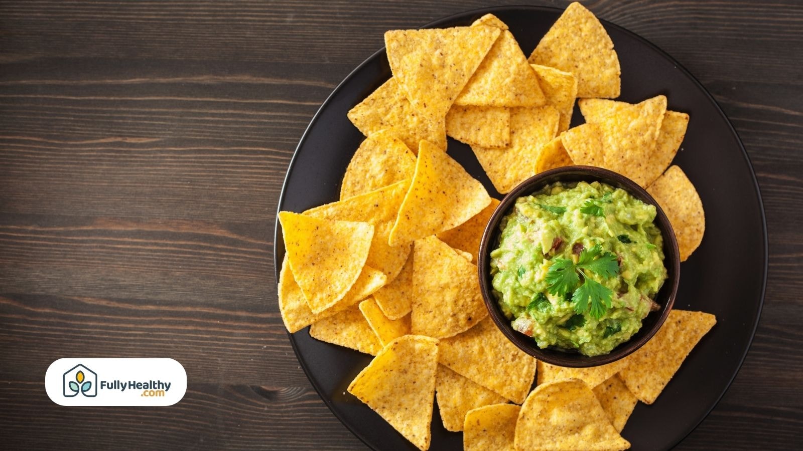 Tortilla chips served with fresh guacamole in a black bowl