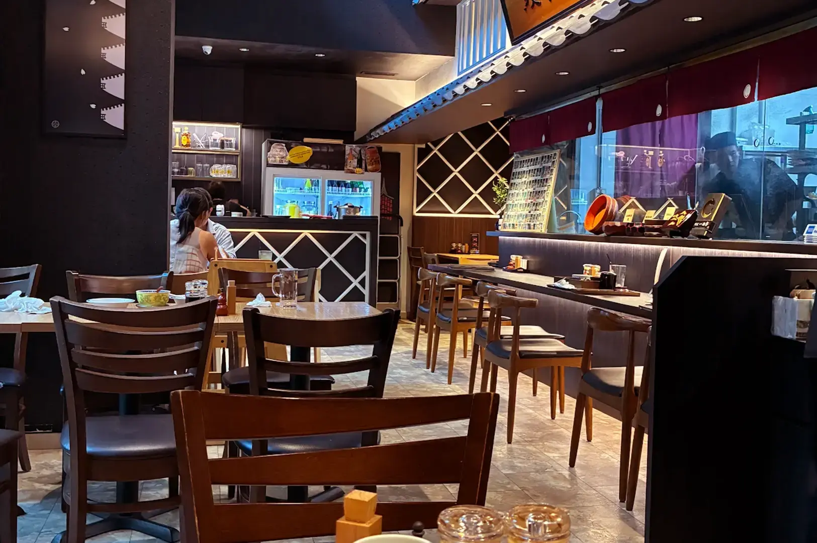 Unagiya Ichinoji dining room with wooden tables, counter seating, warm lighting, and an open kitchen area.