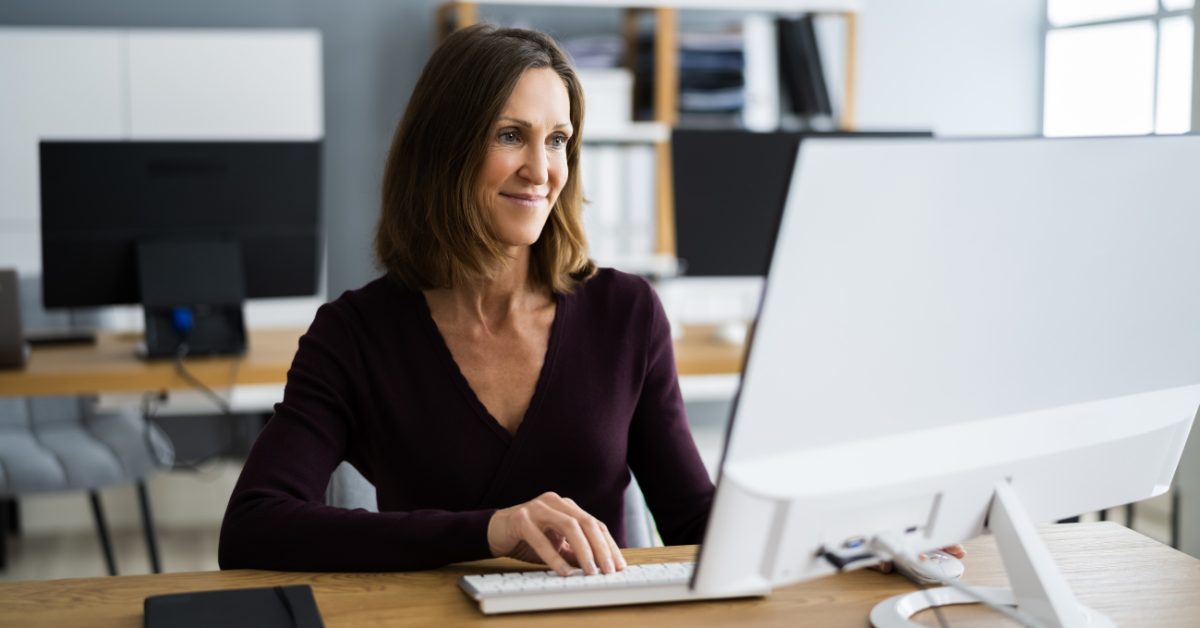 A professional woman working on a desktop in an office; researching federal unemployment quarterly filing.