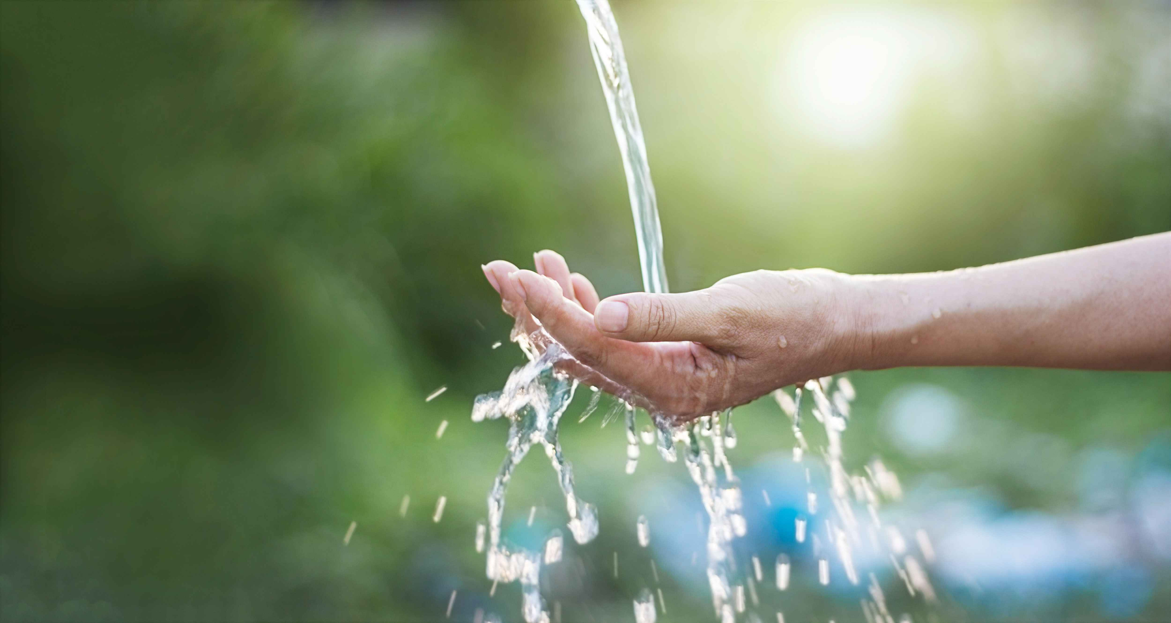 Hand unter einem Wasserstrahl, Naturhintergrund