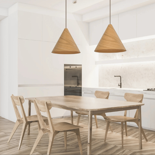 Two Japandi-style pendant lights with conical wooden shades hanging above a minimalist wooden dining table, set in a bright, contemporary kitchen with clean white cabinetry and natural textures.