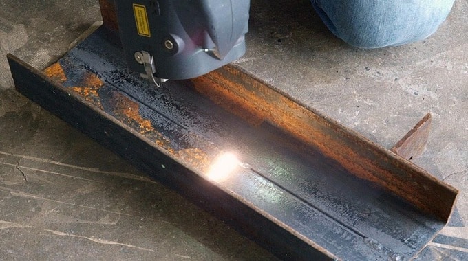 Laser cleaning head removing rust from a metal channel beam.