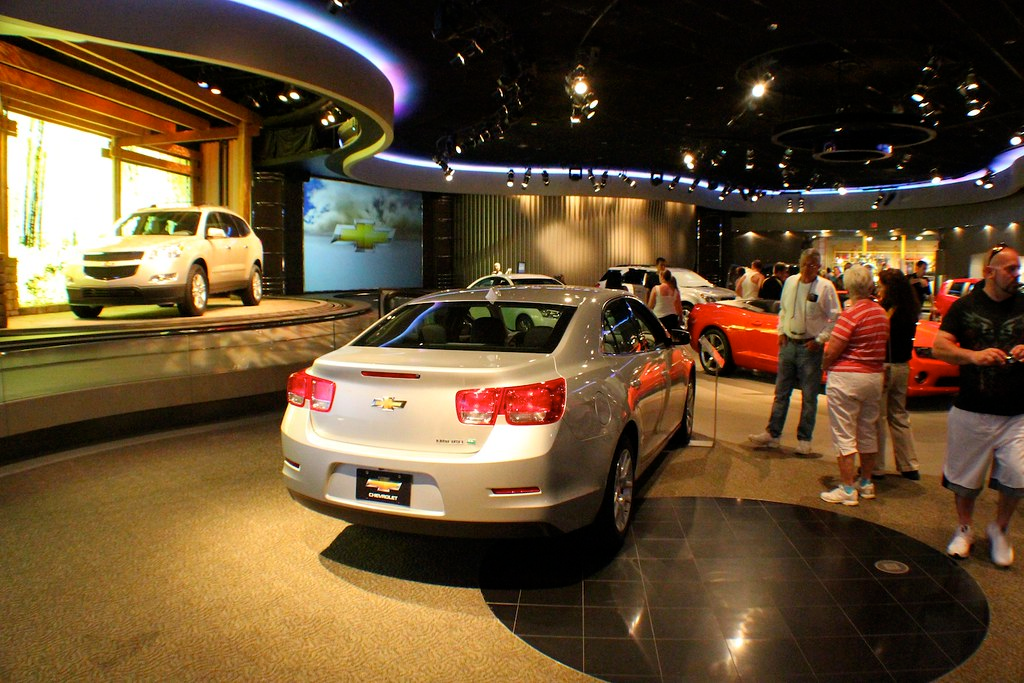 A person looking at a car in a showroom, considering the advantages of paying cash for it