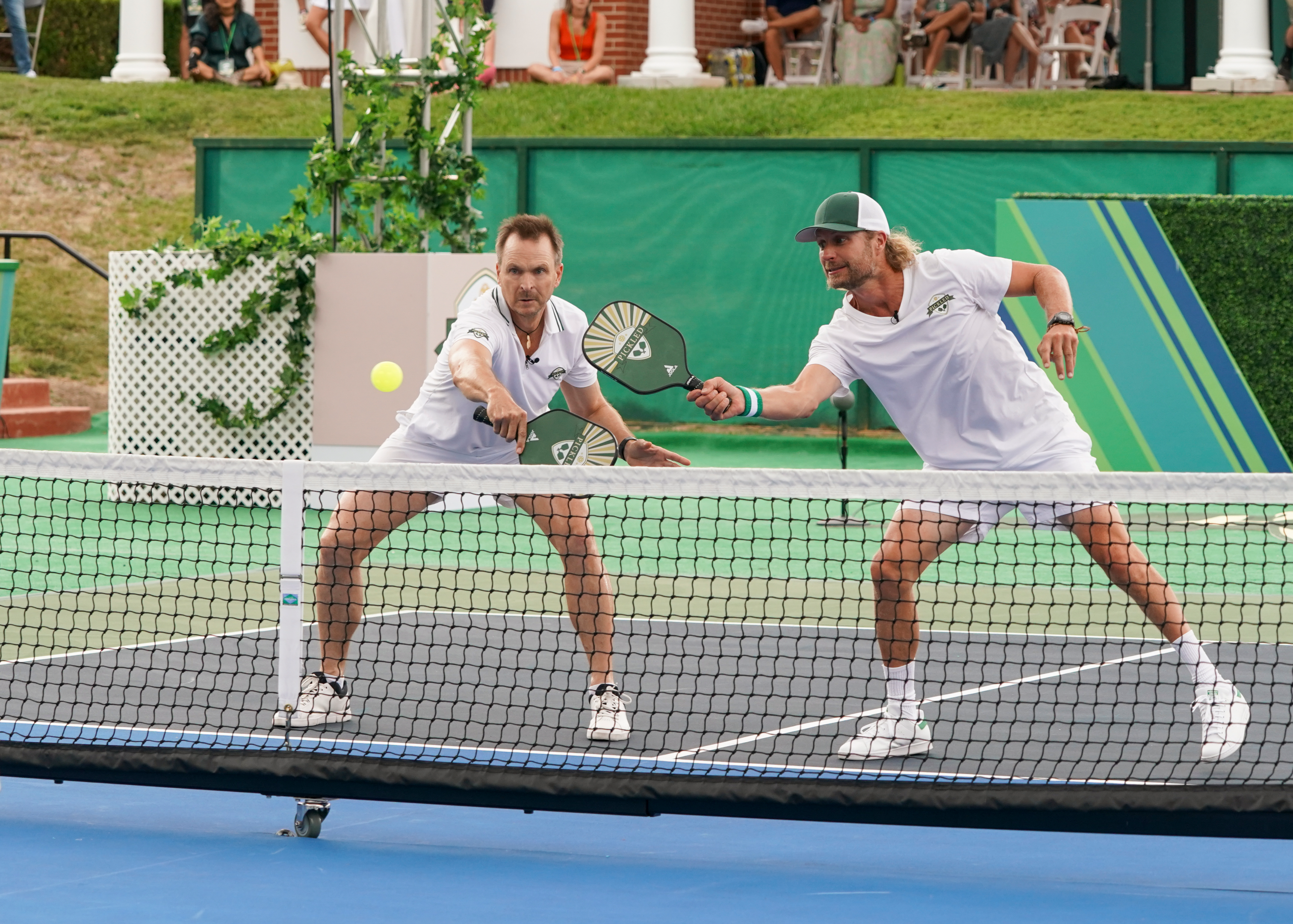 Two players playing pickleball on a court with net