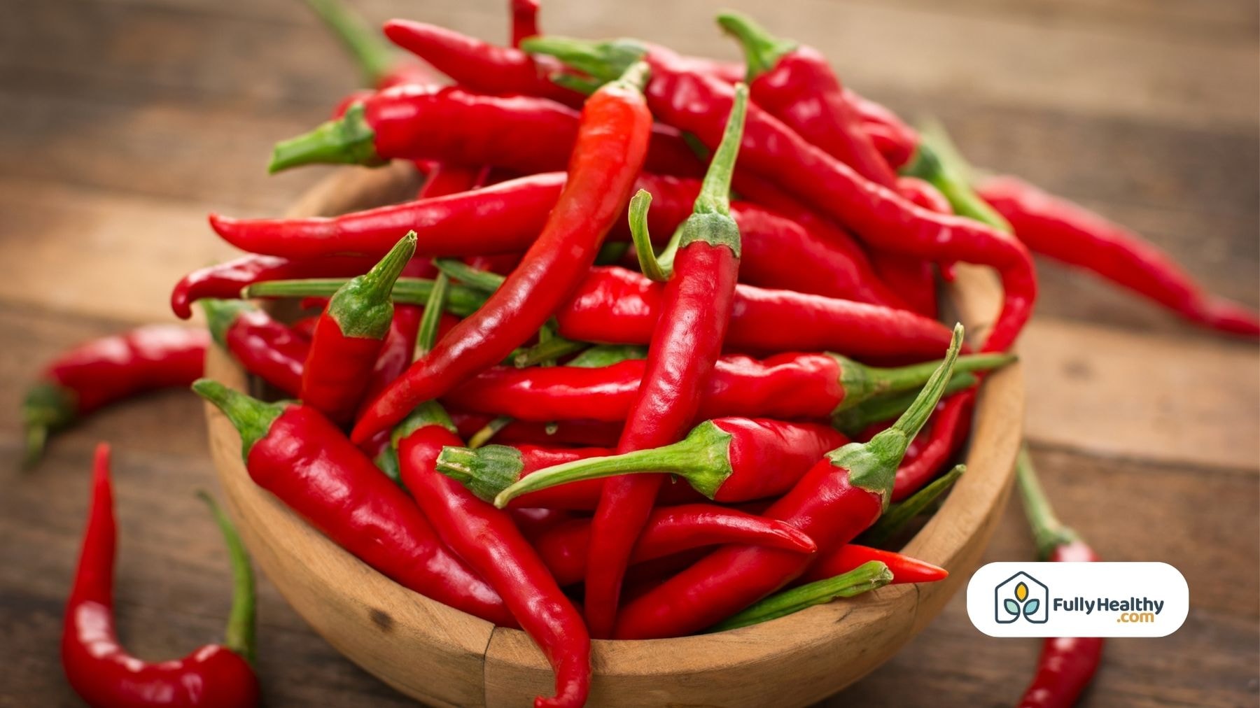 A bowl of vibrant red chili peppers on a wooden surface