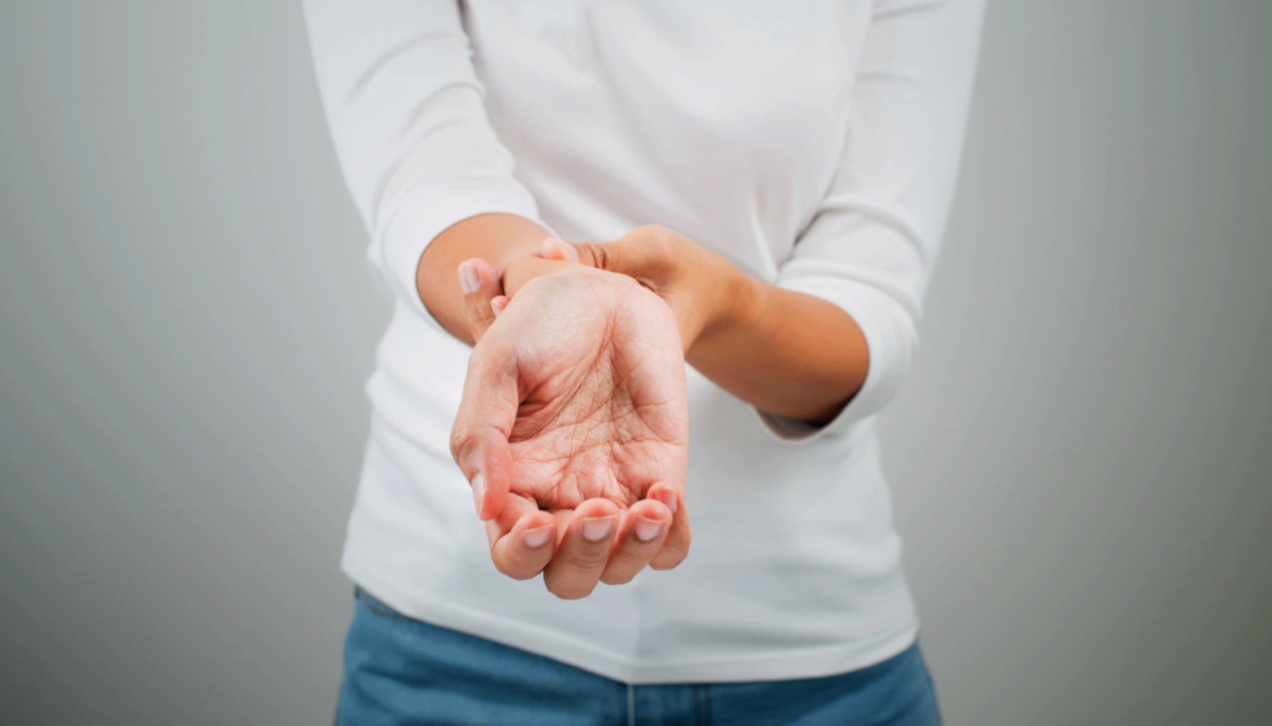 Person holder håndleddet med den andre hånden, antyder smerte eller ubehag i håndleddet.