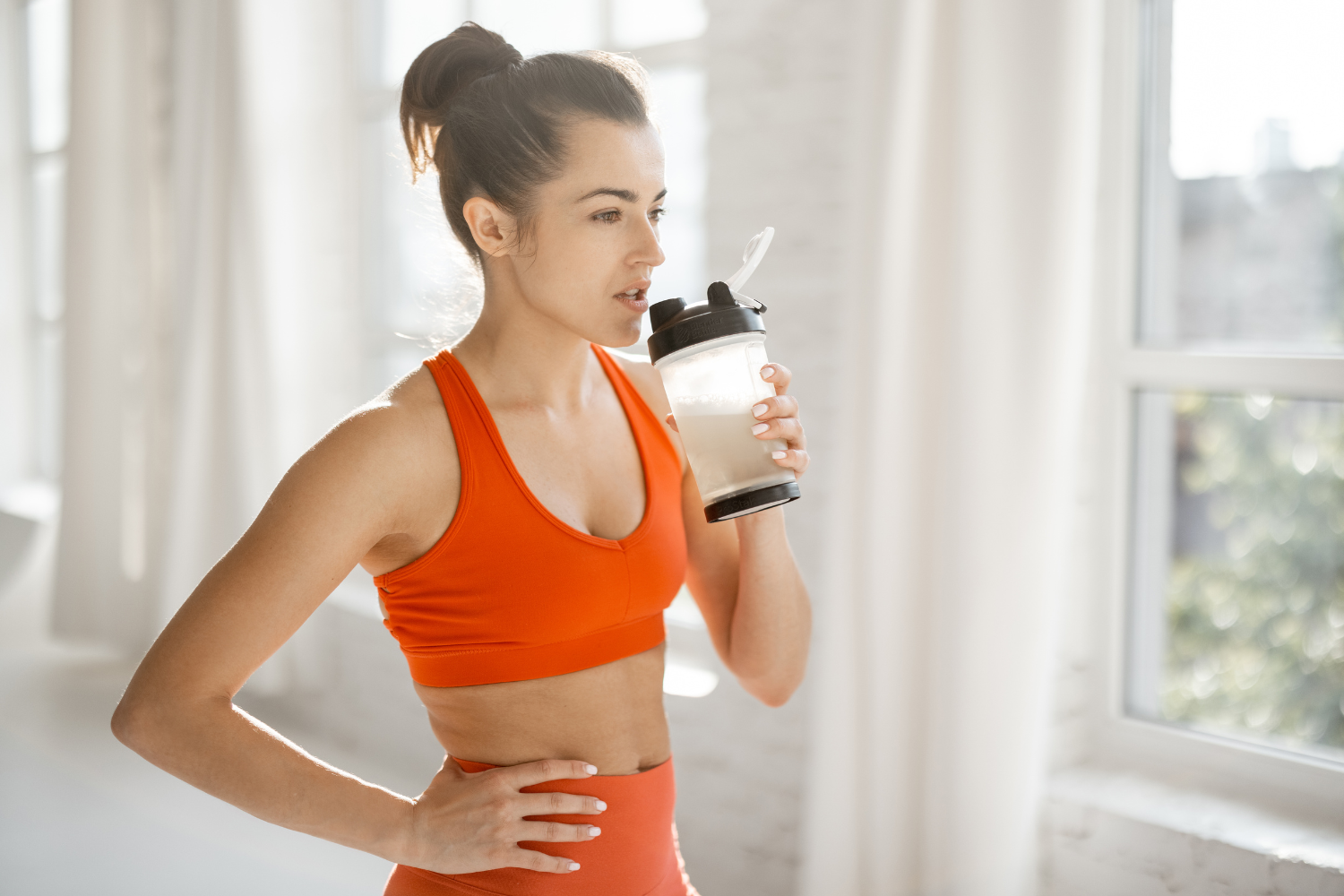 Athlete drinking from a shaker bottle during a workout.