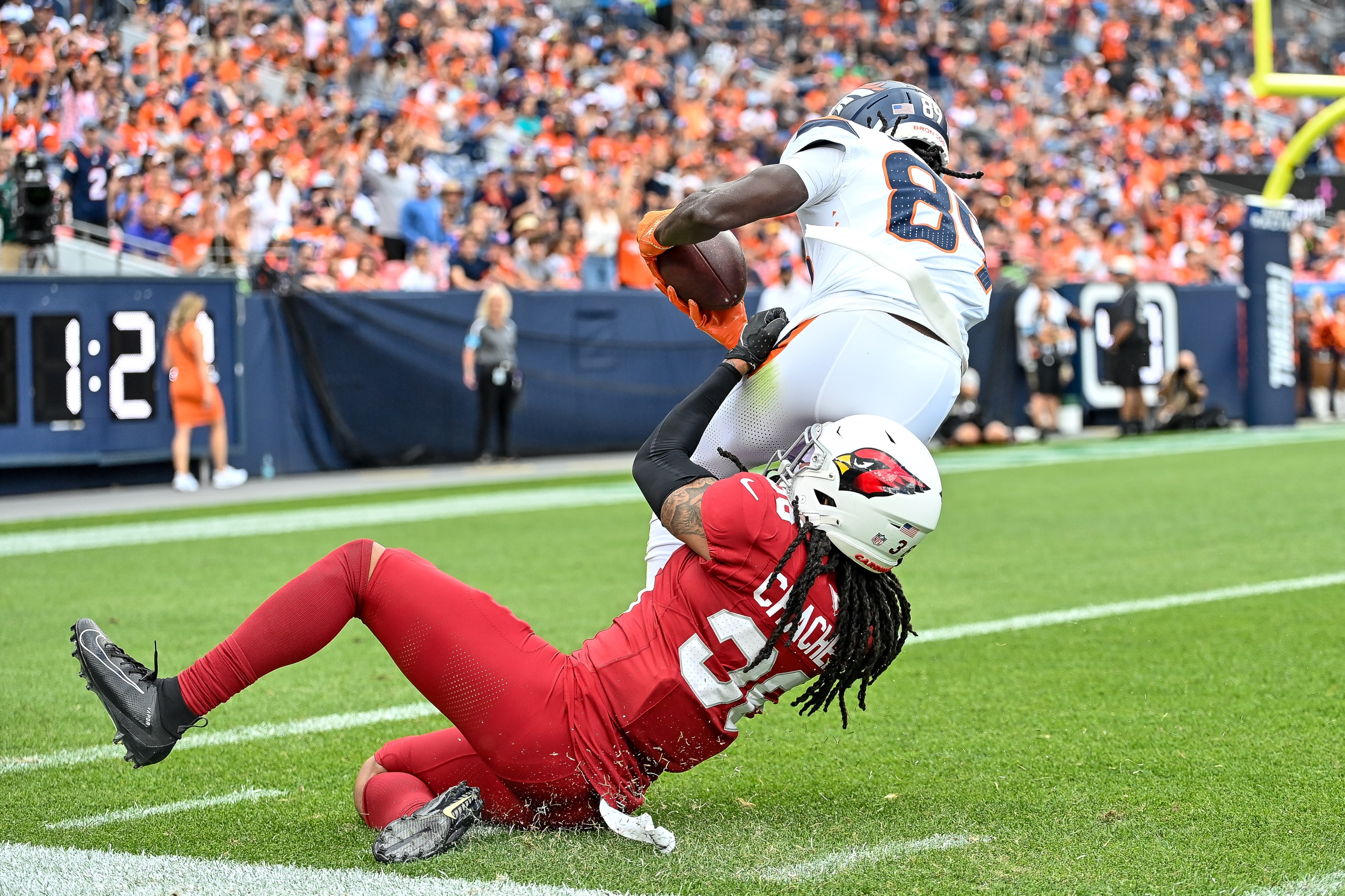 Andre Chachere of the Arizona Cardinals tackles Brandon Johnson of the Denver Broncos during a preseason game on August 25, 2024 in Denver, Colorado.