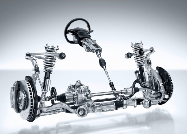 A hyper-realistic image titled 'The Connection Between Steering and Suspension Systems'. The scene should show a detailed view of a car's steering and suspension systems, including components such as the steering wheel, tie rods, rack and pinion, shocks, struts, control arms, springs, and sway bars. The image should be set in a professional auto repair shop with a mechanic explaining the connection between the systems to a car owner. Include labels for each component and arrows showing how the systems interact. The background should emphasize a clean, organized workshop with tools and equipment. The title 'The Connection Between Steering and Suspension Systems' should be prominently displayed.
