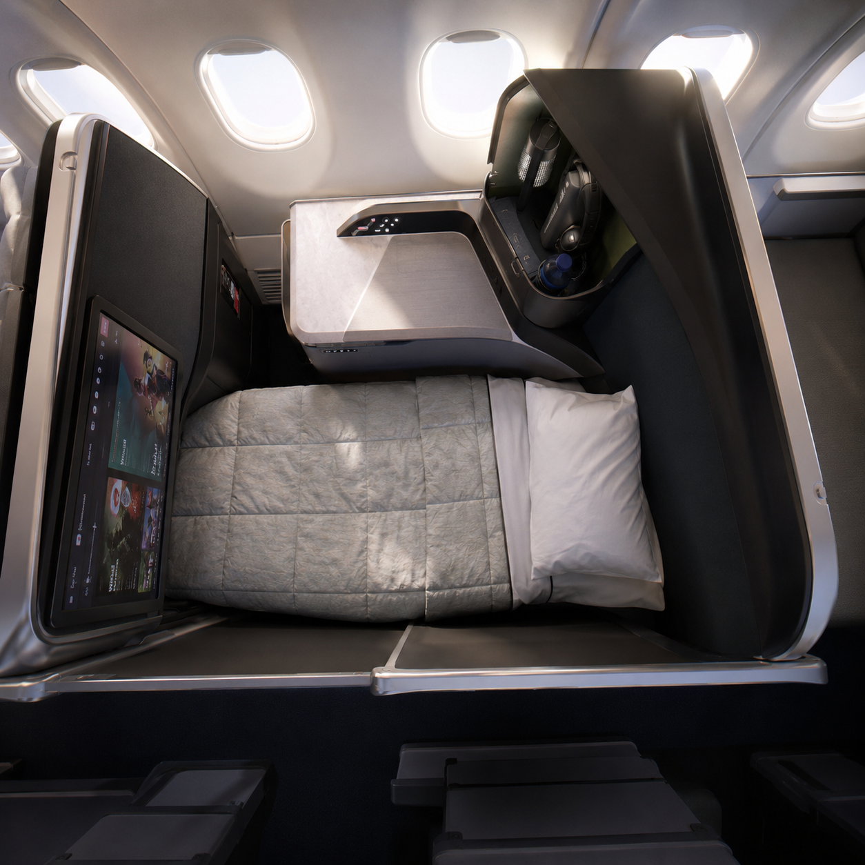 Business class suite with a fully flat bed, grey quilted bedding, white pillow, large entertainment screen, storage console and high privacy walls.