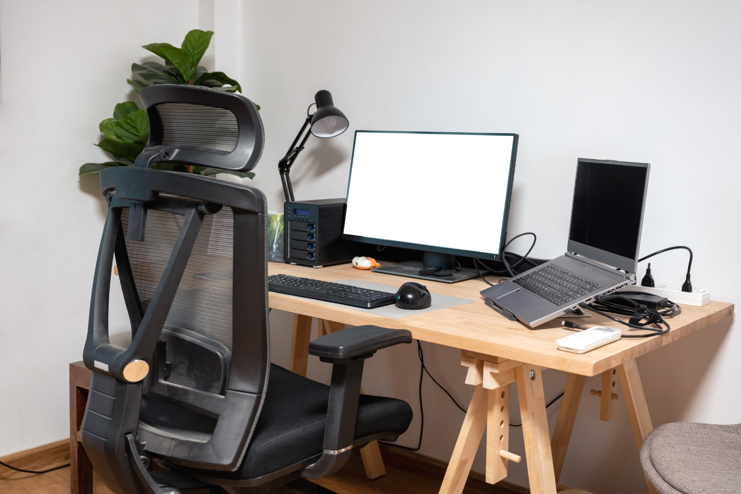 Ergonomic chair and two laptops with a power surge at a remote worker’s desk.