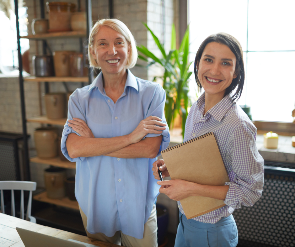 an older and younger woman stand together in a ceramics studio