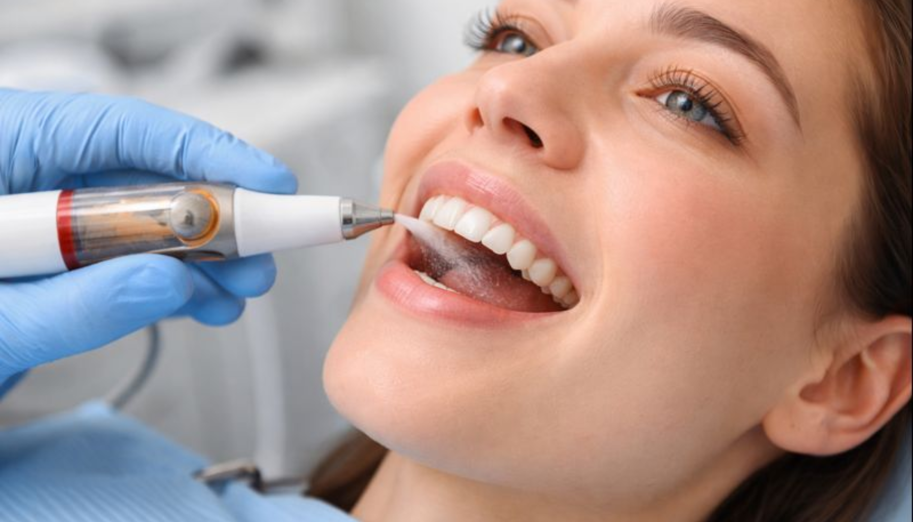 Kvinne får profesjonell AIRFLOW-tannrengjøring med skånsomt pulver og vannspray hos tannpleier i klinikk.