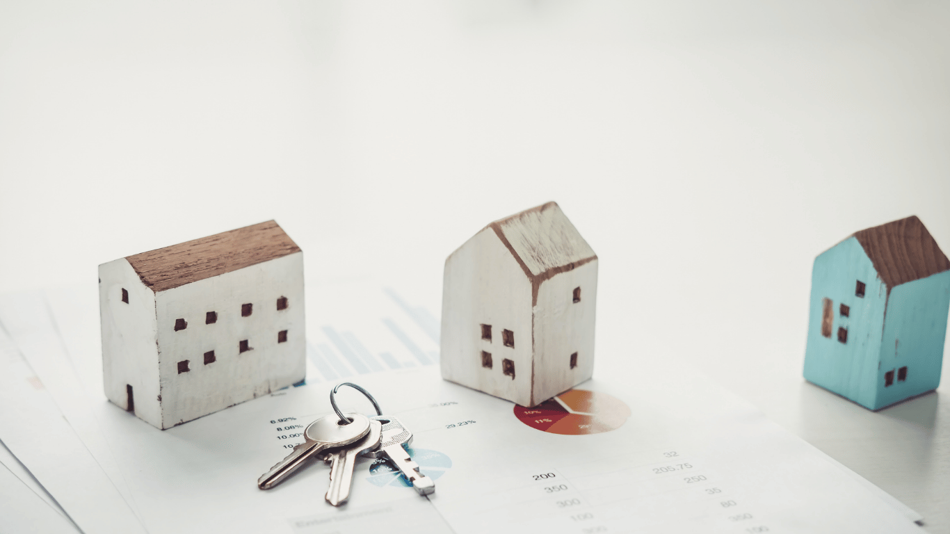 Wooden house models and keys placed on financial charts representing rising rental demand and property investment opportunities in the housing market.