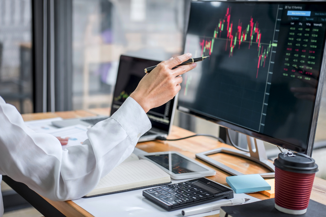 Business broker pointing at a trading graph on computer screen during financial analysis