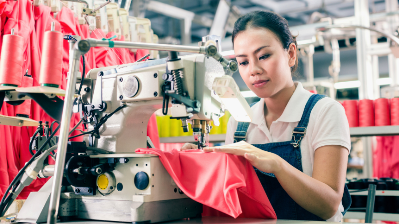 A person working on a sewing machine in a fabric factory
