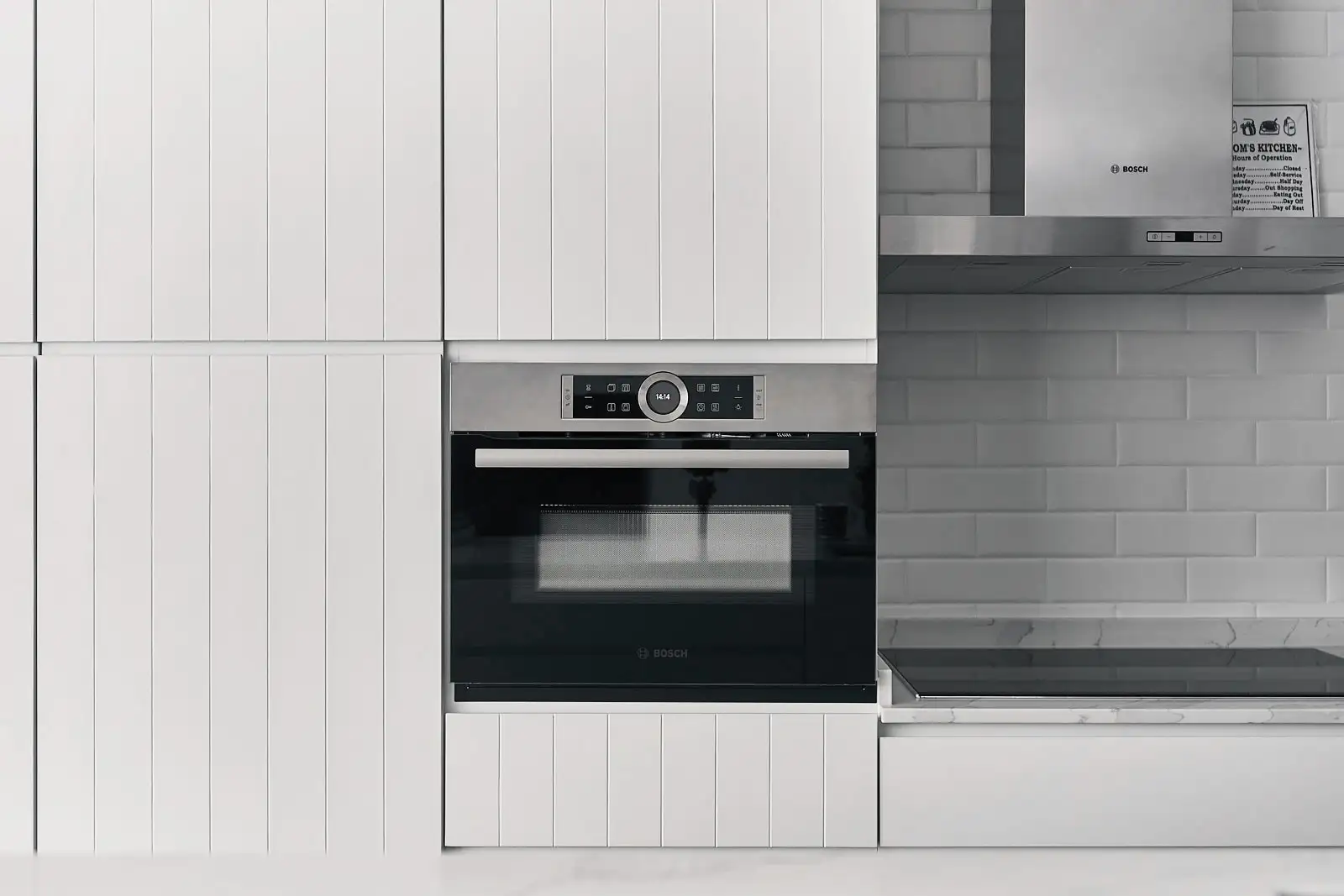 Minimalist house kitchen with integrated Bosch oven, white panel cabinetry and subway tiles