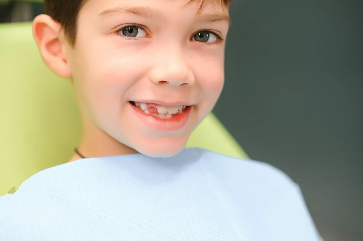 Dental hygienist cleans smiling child's teeth during professional pediatric examination.