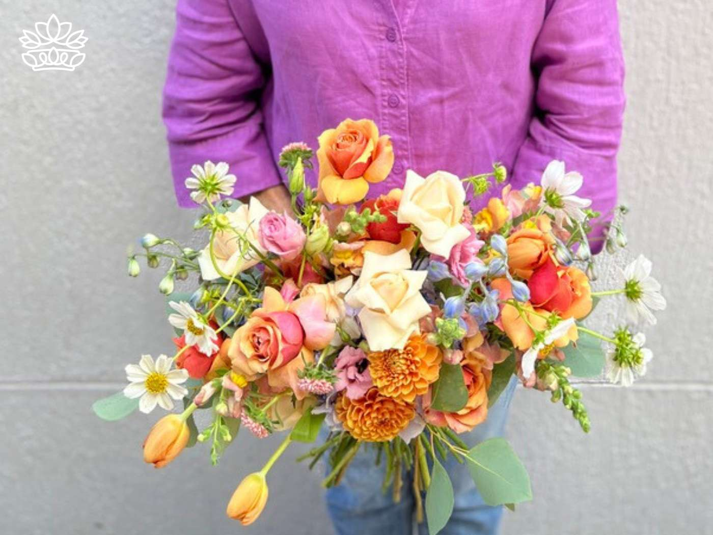 Person in a purple shirt holding a vibrant bouquet from the Easter Flowers Collection, symbolizing the joy of the Christian faith on Sunday morning, available for same day delivery by Fabulous Flowers and Gifts.