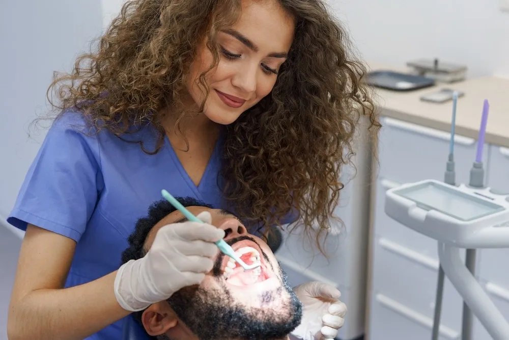 Dental professional performing a detailed oral examination using specialized lighting equipment to provide optimal patient care in modern treatment setting.