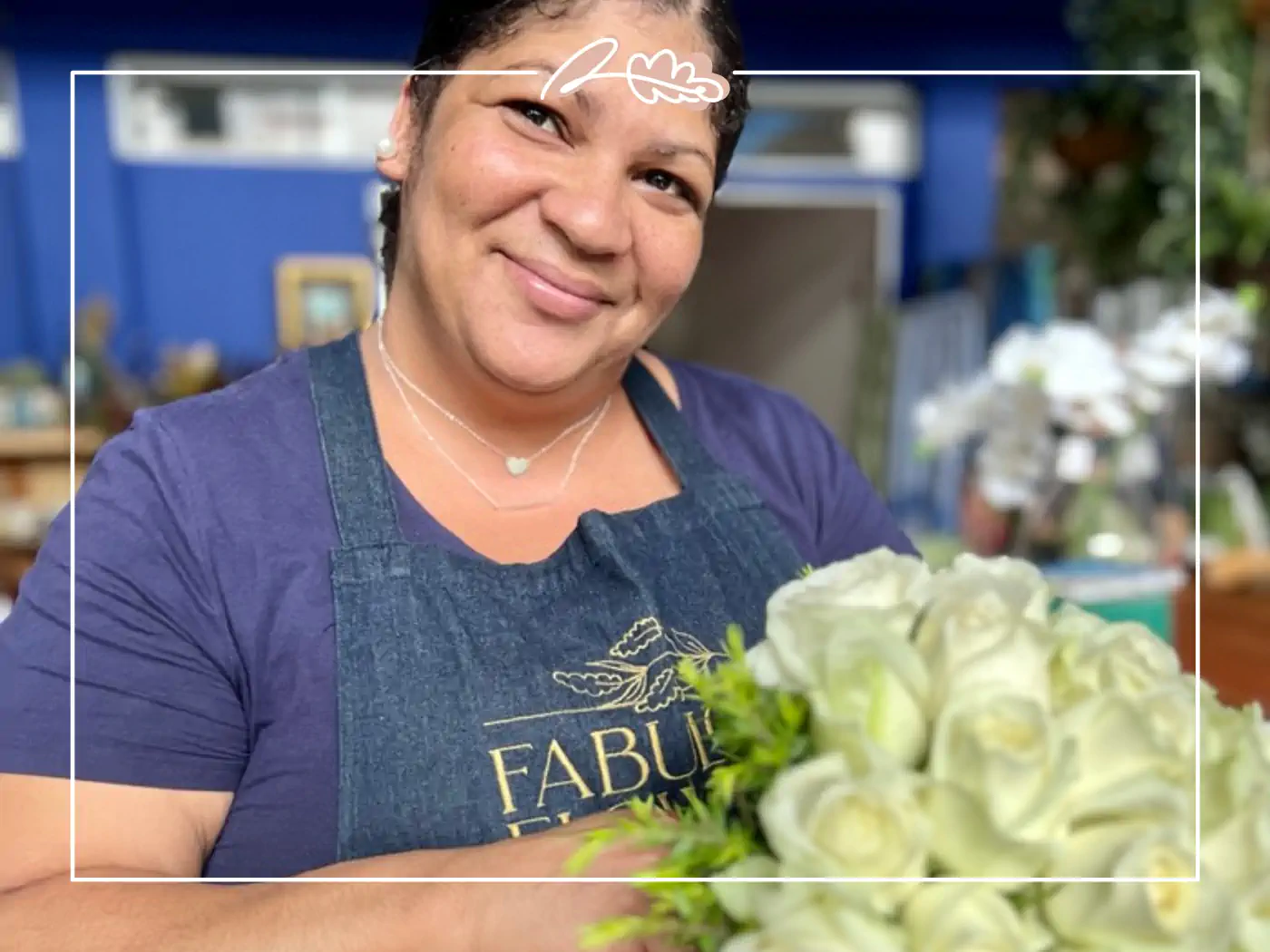 A smiling florist at Fabulous Flowers and Gifts holding a bouquet of white roses. Your Perfect Bouquet of Flowers.