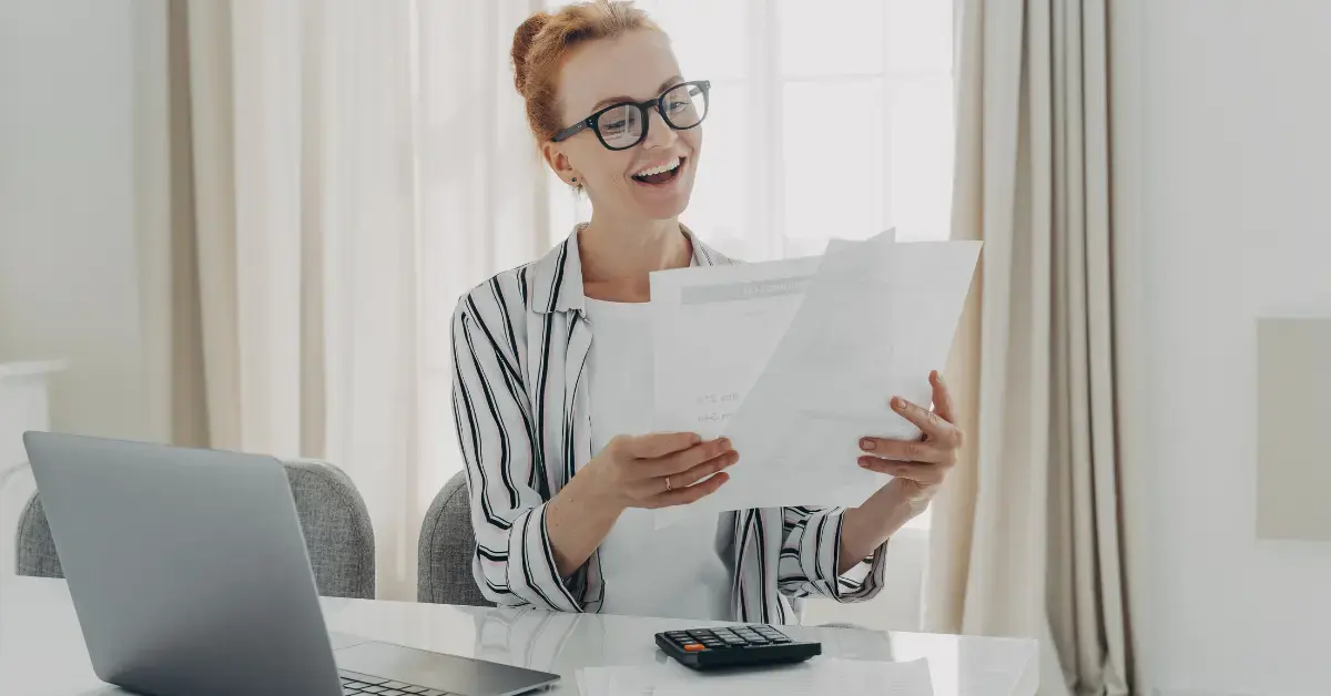 Woman reviewing income reports and planning safe harbor rules for estimated taxes.